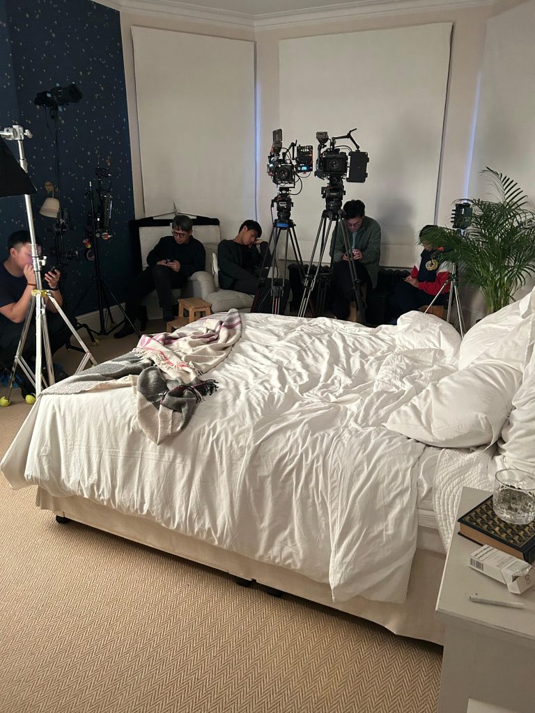 Professional film crew coordinating intimate bedroom scene with multiple cameras